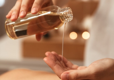 Mujer vertiendo botella de aceite en la mano